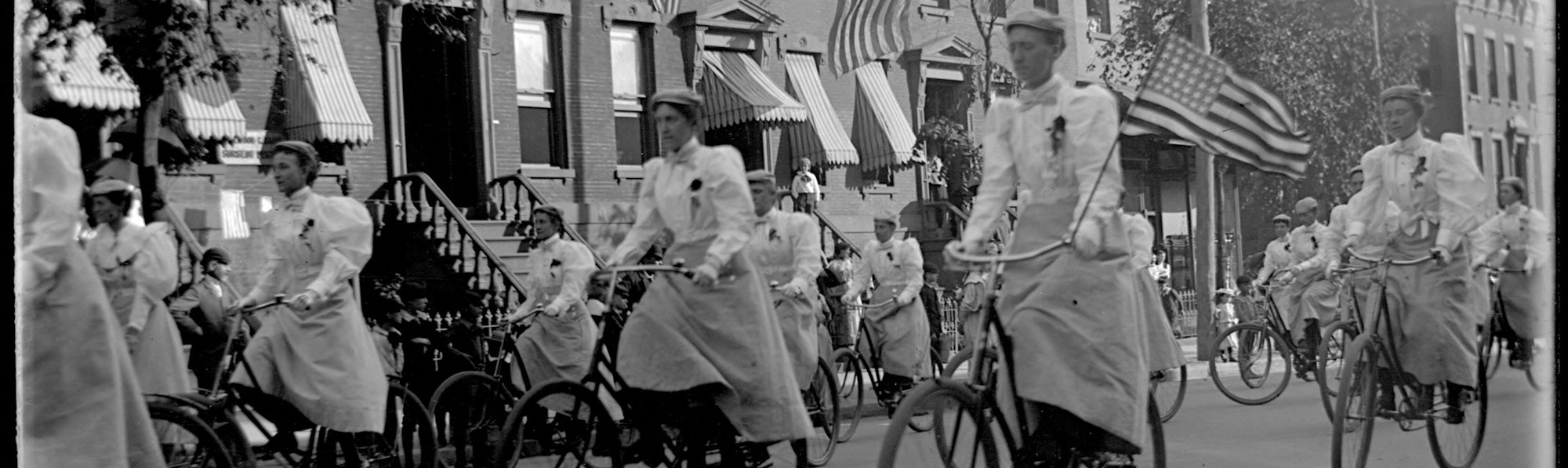 a parade of women in white dresses in the Bronx riding bicycles in 1898