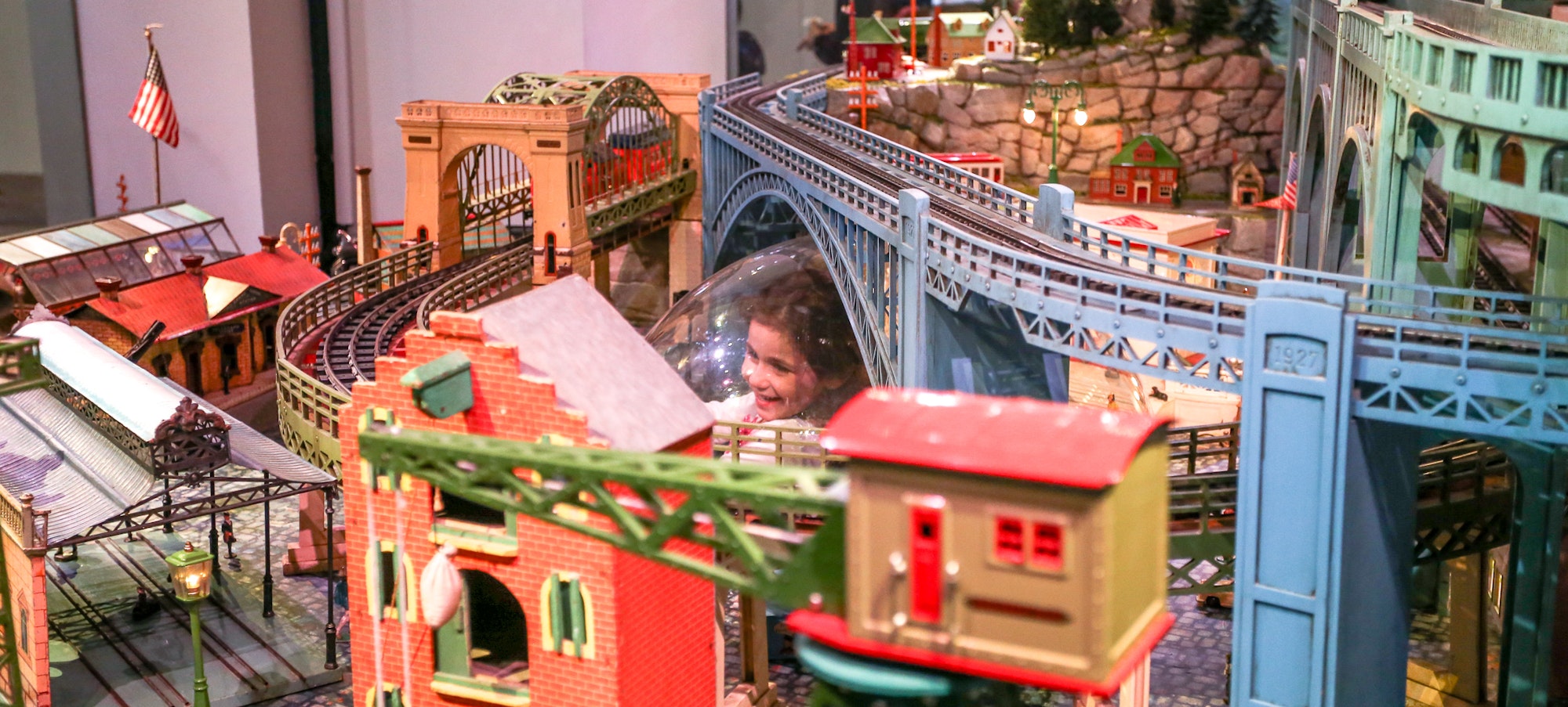 a young girl looking up from the bubble of the Holiday express train display