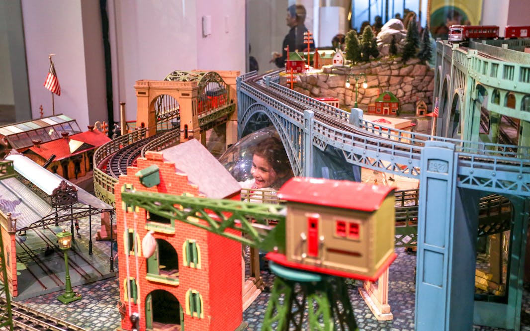 a young girl looking up from the bubble of the Holiday express train display