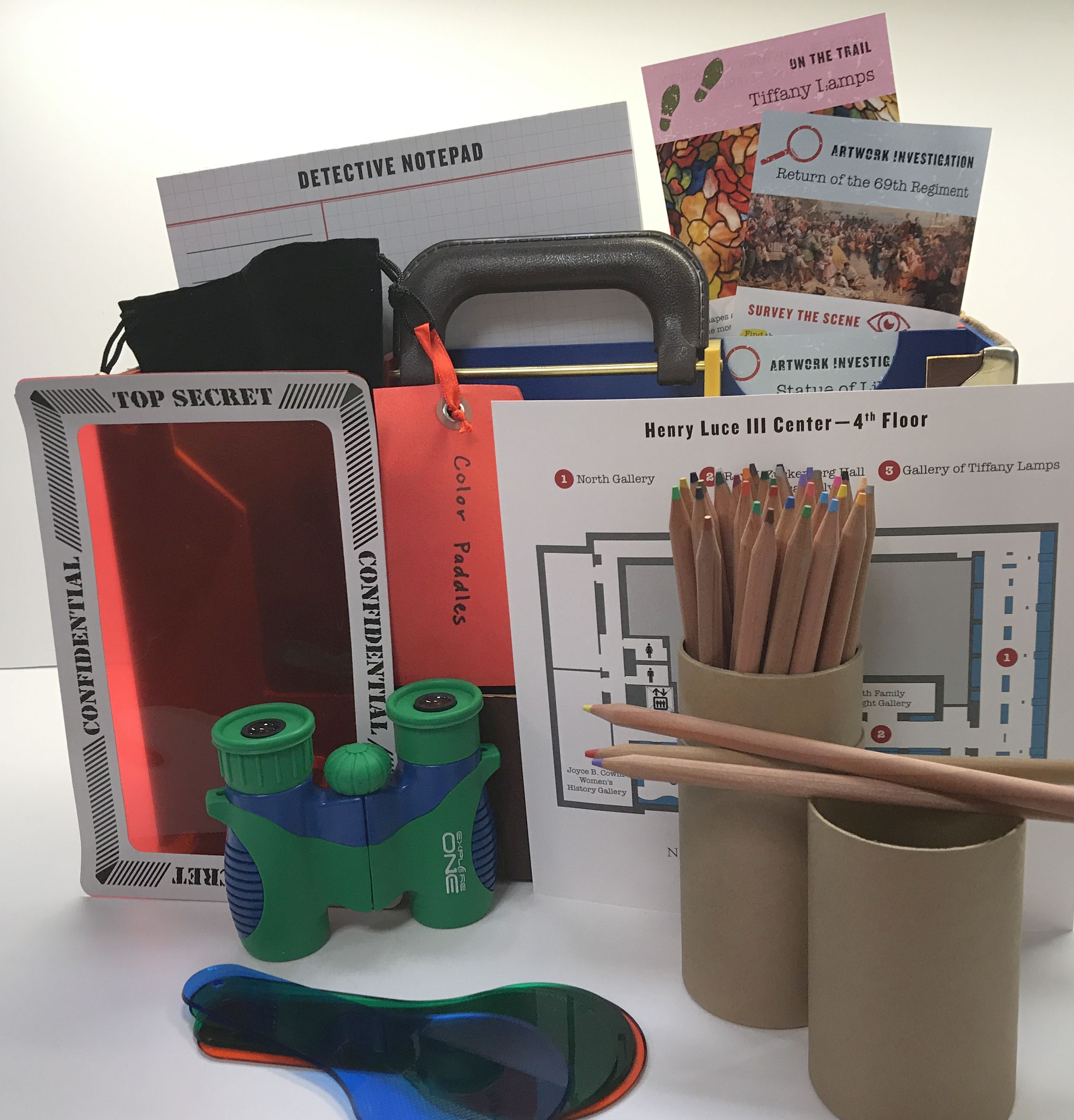 photo of the history detective briefcase with activities shown outside including colored pencils, binoculars, and notepads