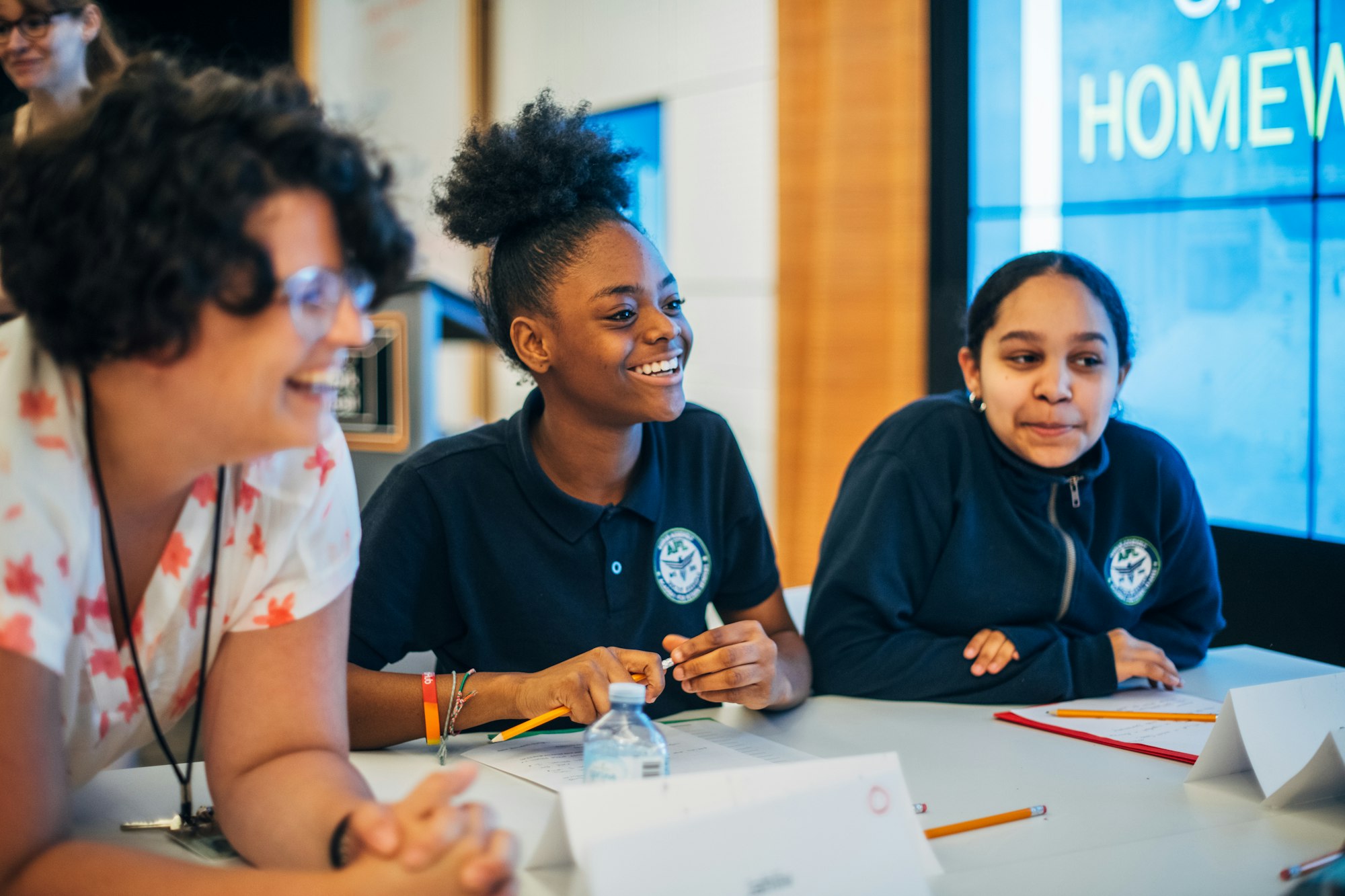Two students and an educator listening to each other during a class session.