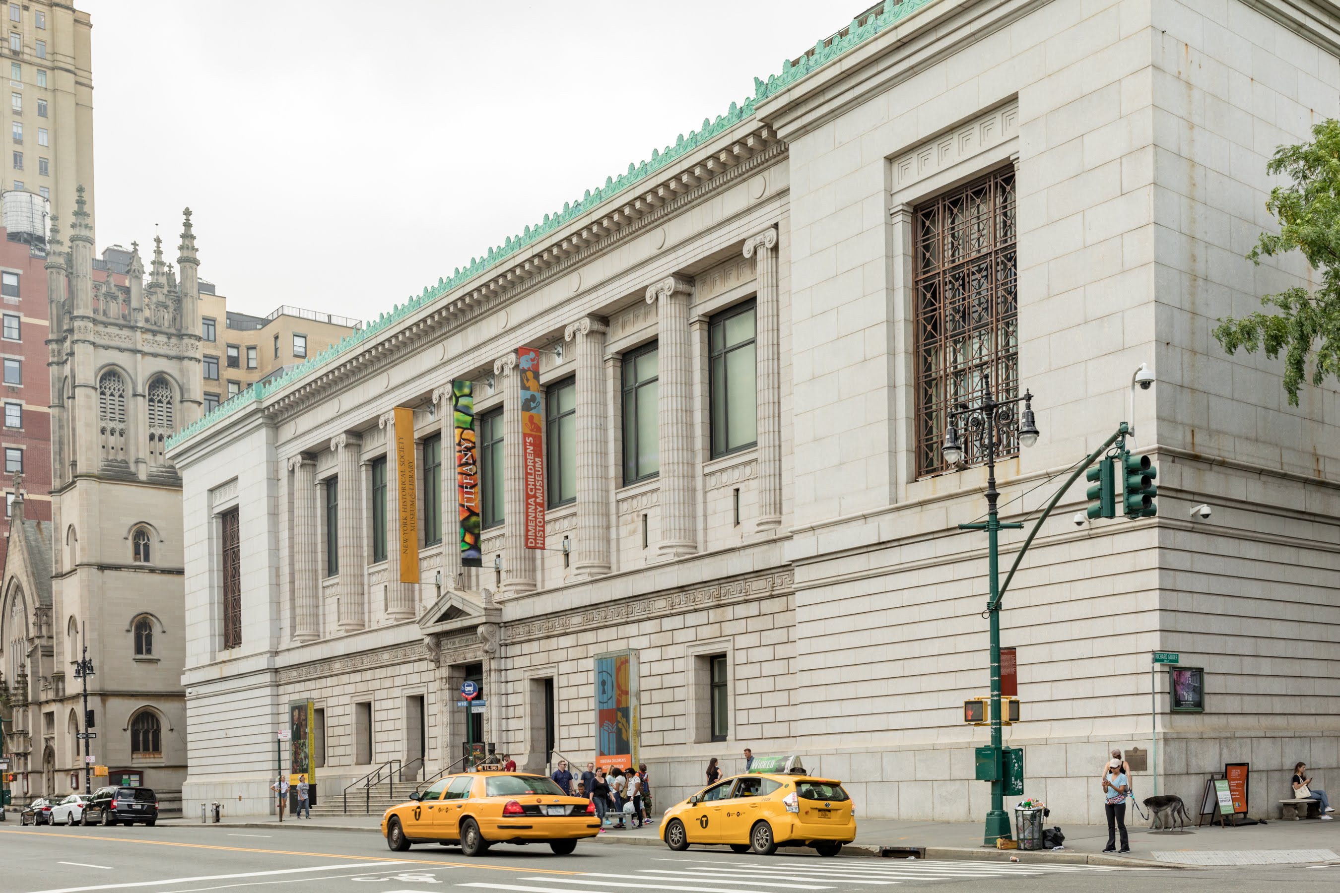 The New-York Historical facade during the day with cabs passing by and people crowded outside