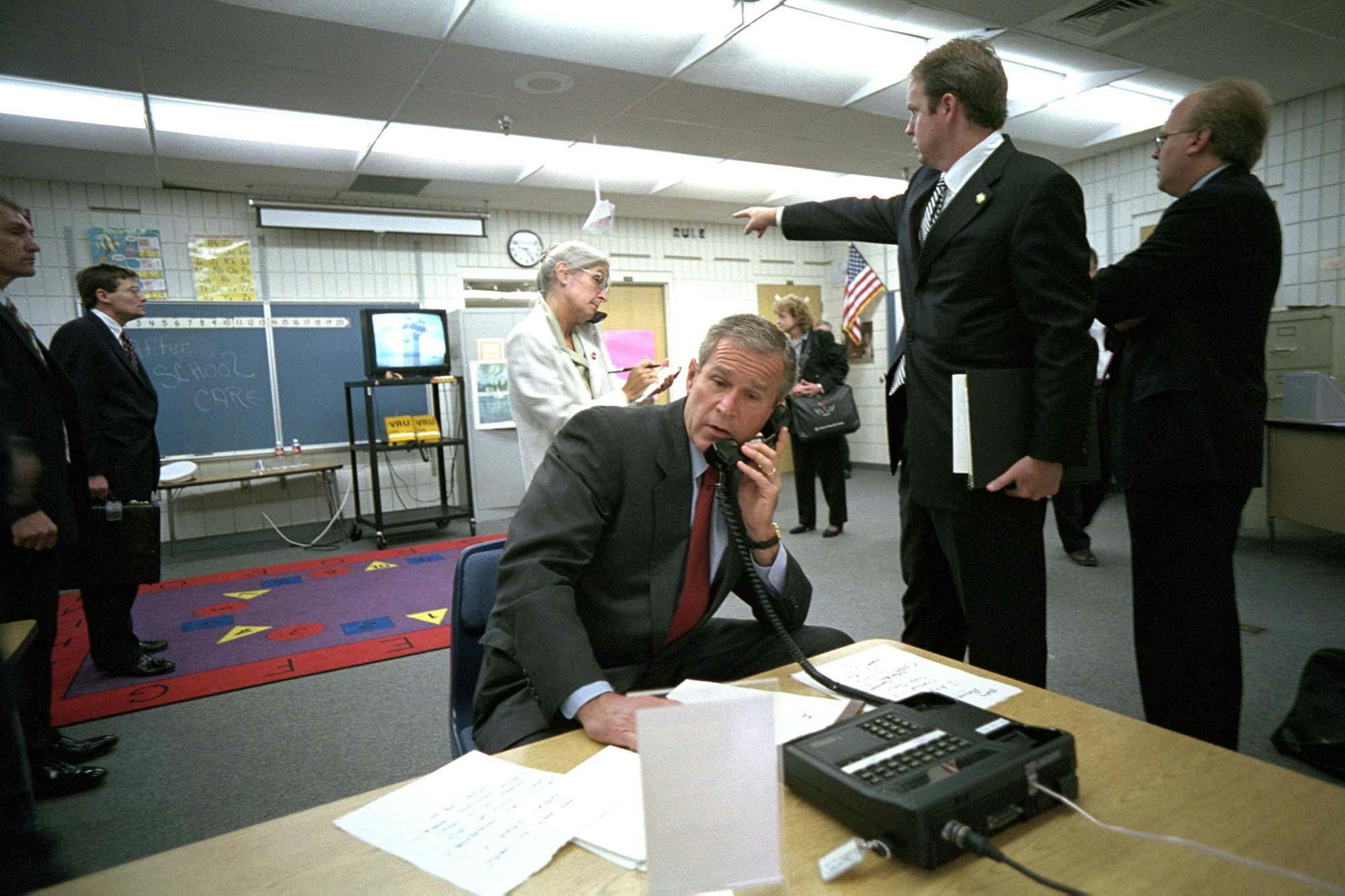 Director of Communications Dan Bartlett points to news footage of the World Trade Center Towers burning, September 11, 2001, as President George W. Bush gathers information about the attack in a classroom at Emma E. Booker Elementary School in Sarasota, Florida. Courtesy of the George W. Bush Presidential Library and Museum, P7058-20A.