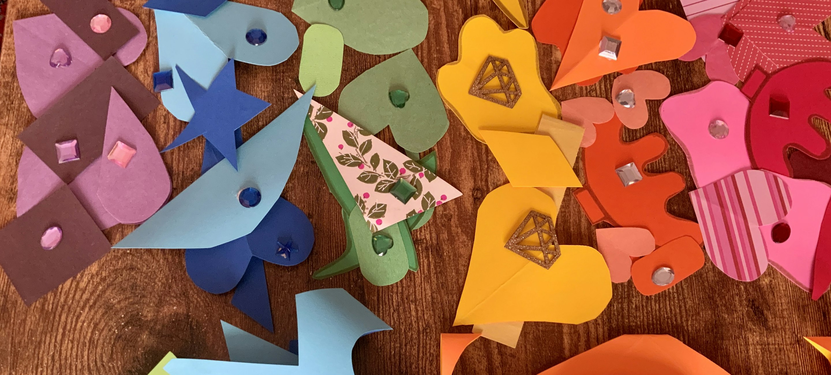 colorful shapes cut out and laid on a table with a pair of scissors nearby