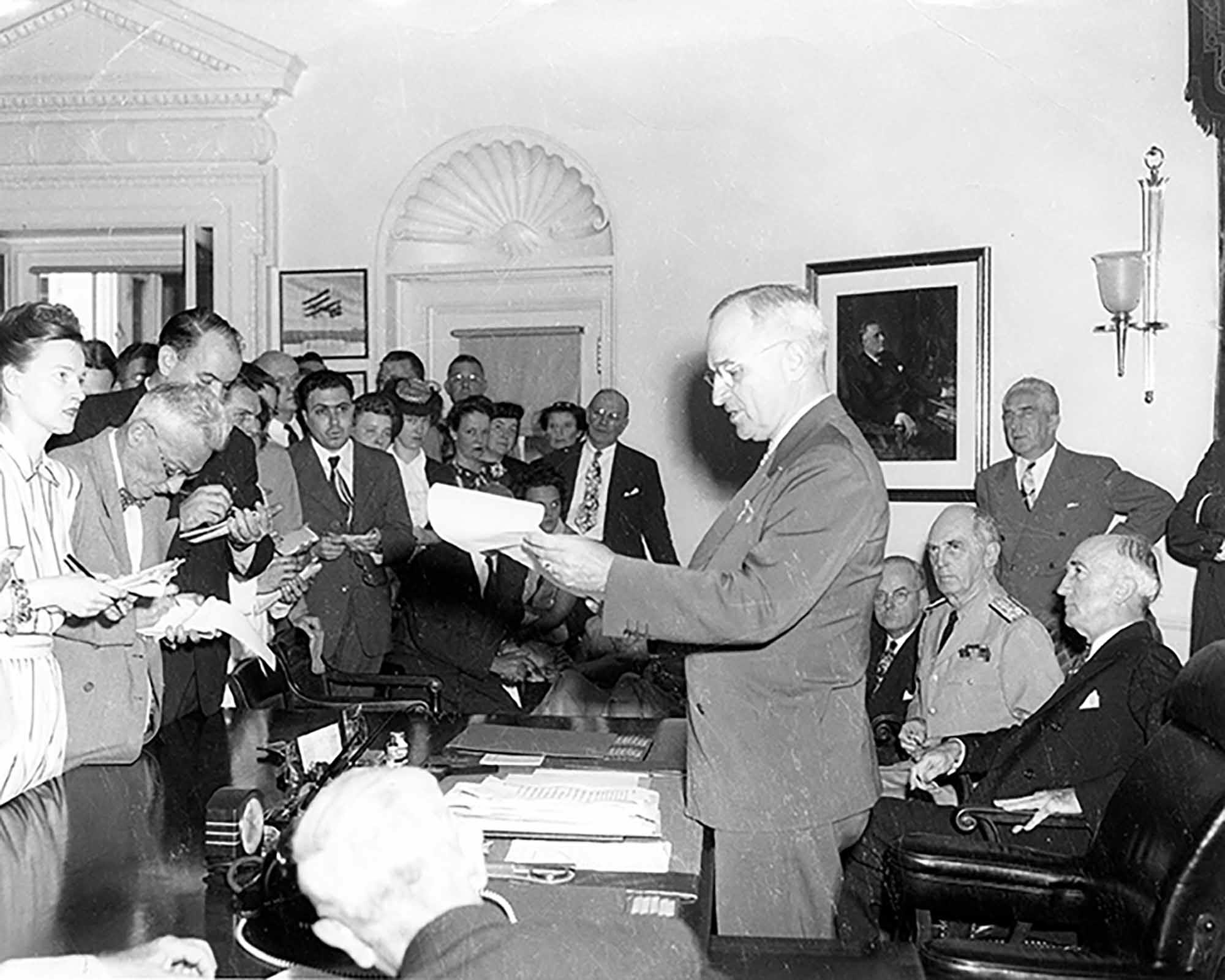 President Harry S. Truman announcing the surrender of Japan, ending World War II, to assembled reporters in the Oval Office. August 14, 1945. Abbie Rowe, National Park Service. Harry S. Truman Library.