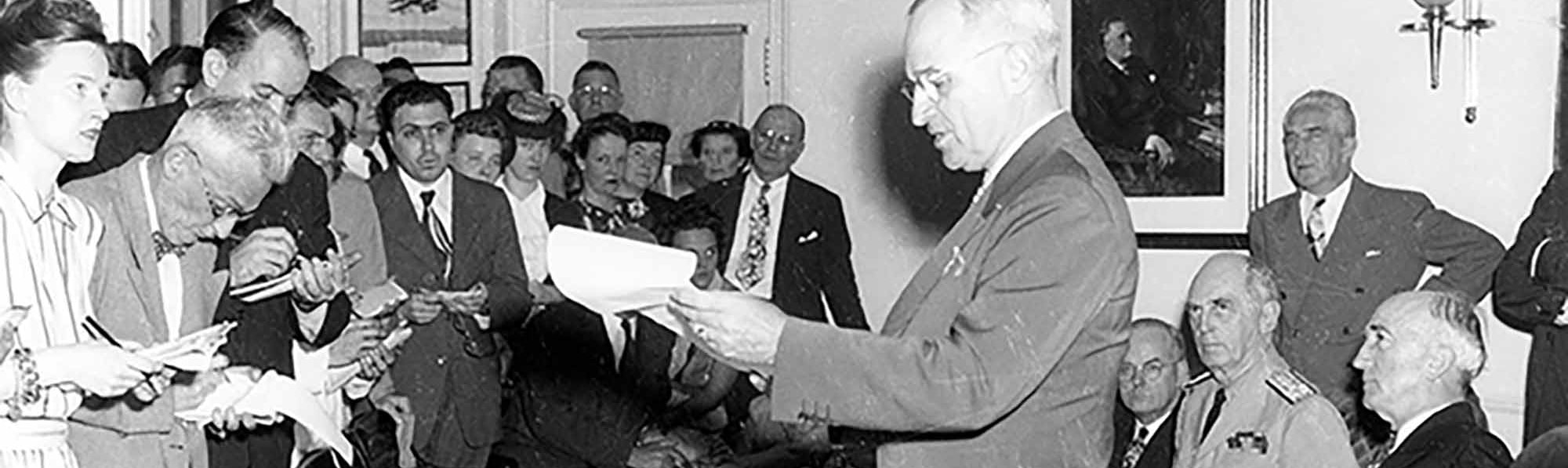 President Harry S. Truman announcing the surrender of Japan, ending World War II, to assembled reporters in the Oval Office. August 14, 1945. Abbie Rowe, National Park Service. Harry S. Truman Library.