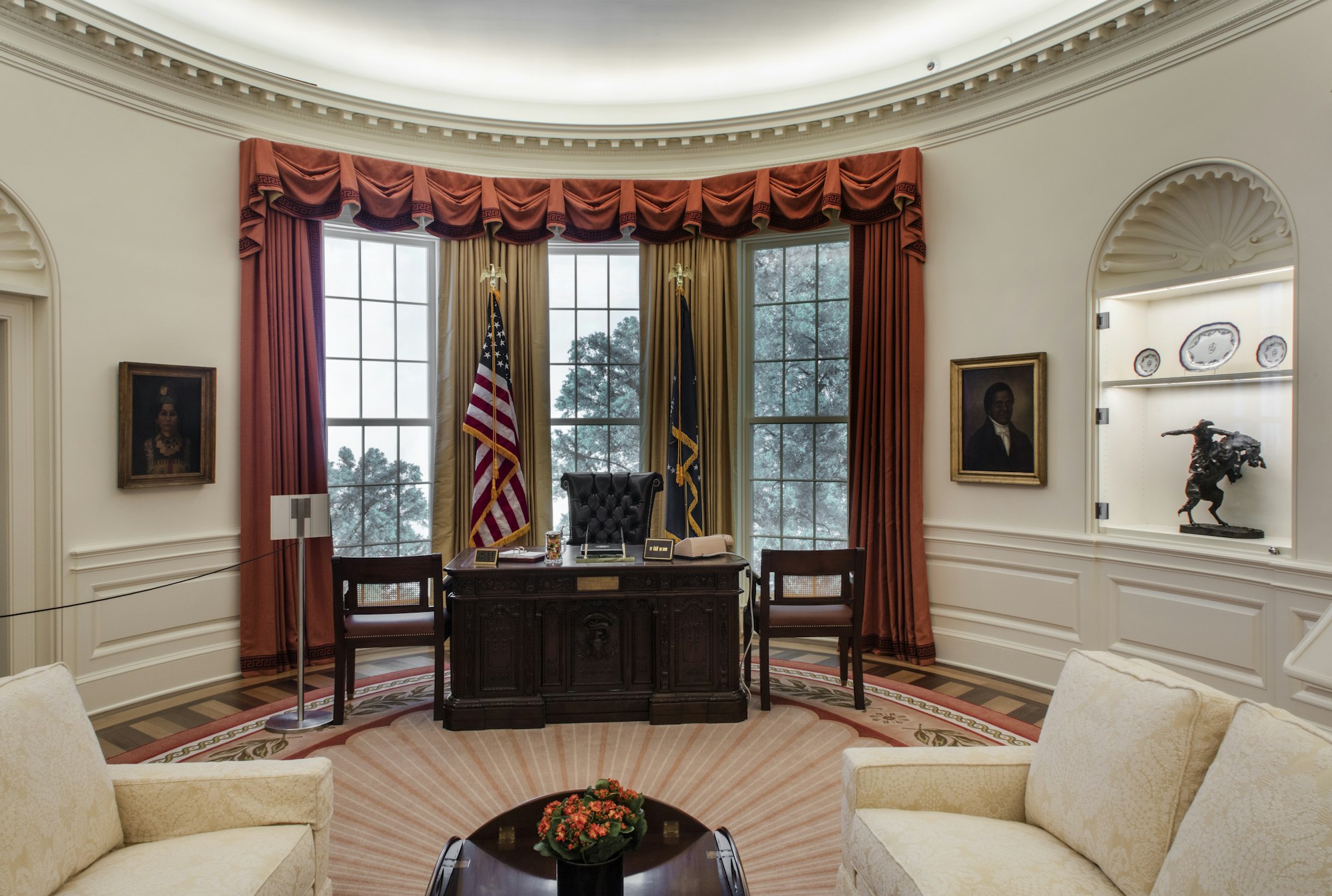 A view inside our Oval Office re-creation, facing the Resolute desk with the flags behind it.