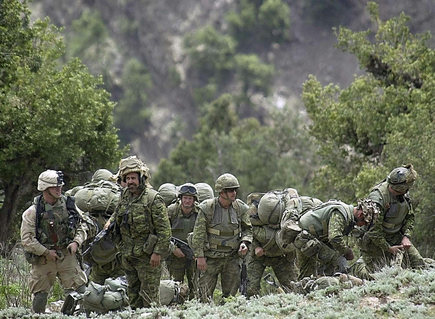 Photo, SSGT Jeremy T. Lock, USAF. Coalition soldiers from US, Canada, and Afghanistan at a landing zone in 7,500-foot mountains in the Tora Bora region of Afghanistan. They are part of the over 400 members of Operation Torii who are looking for Osama Bin Laden. May 4 2002. Everett/Shutterstock.