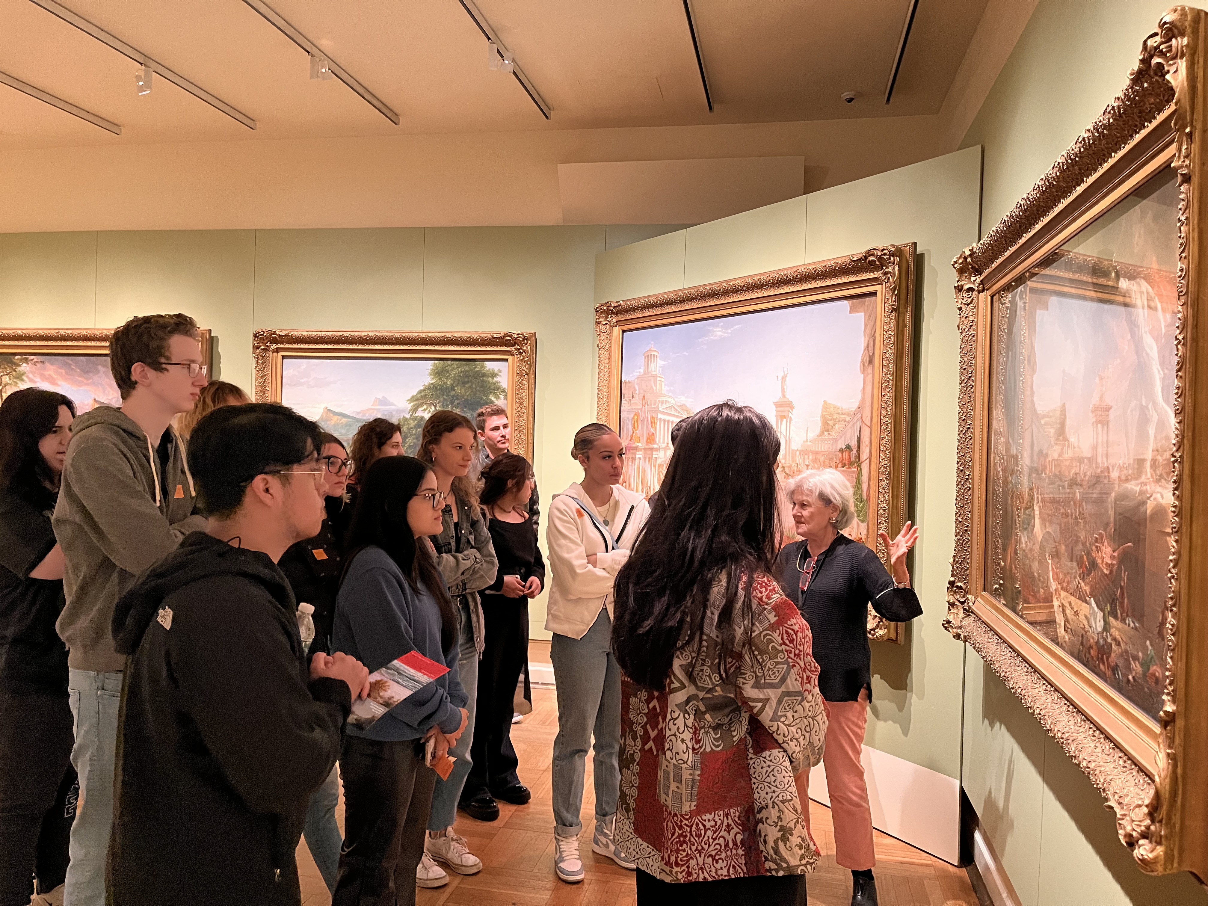 a docent leading a tour of visitors as they stand in front of a course of empire