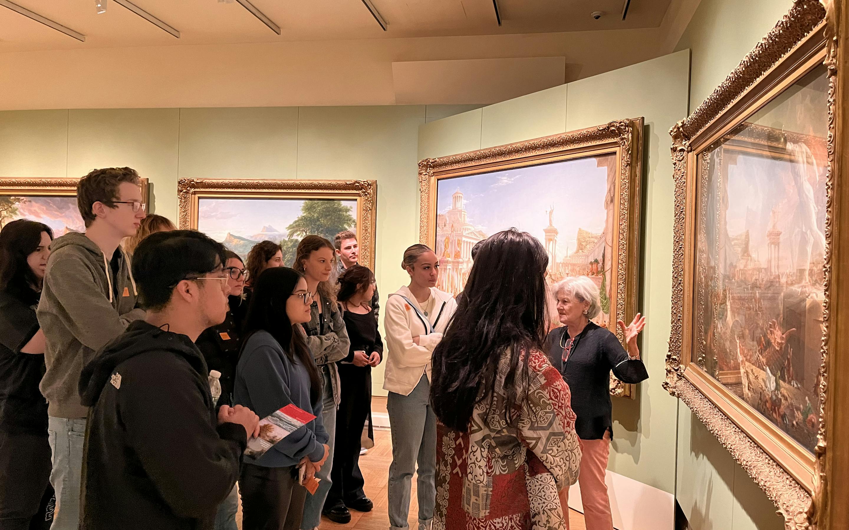a docent leading a tour of visitors as they stand in front of a course of empire