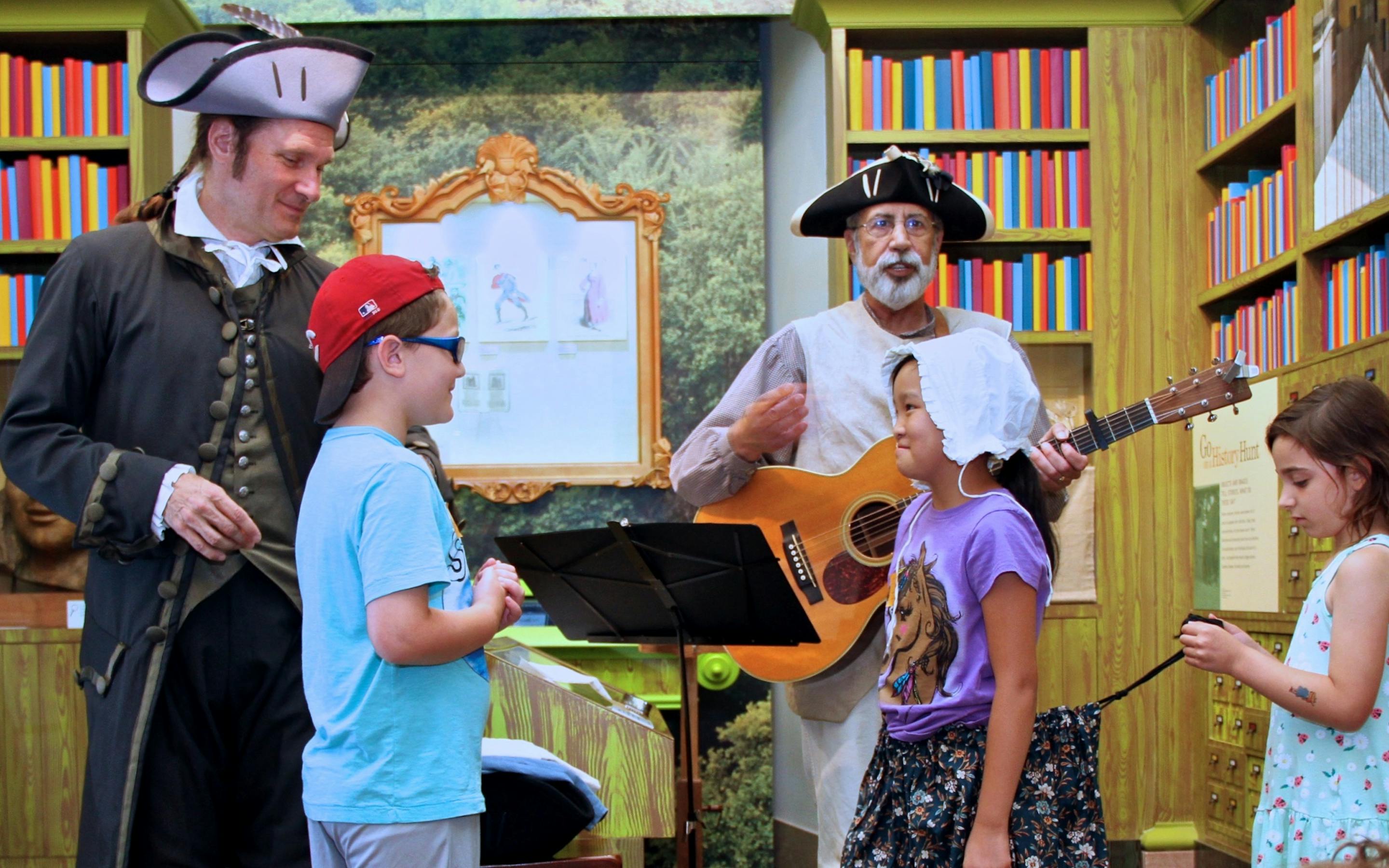 living historians interact with a group of children in the children's museum library