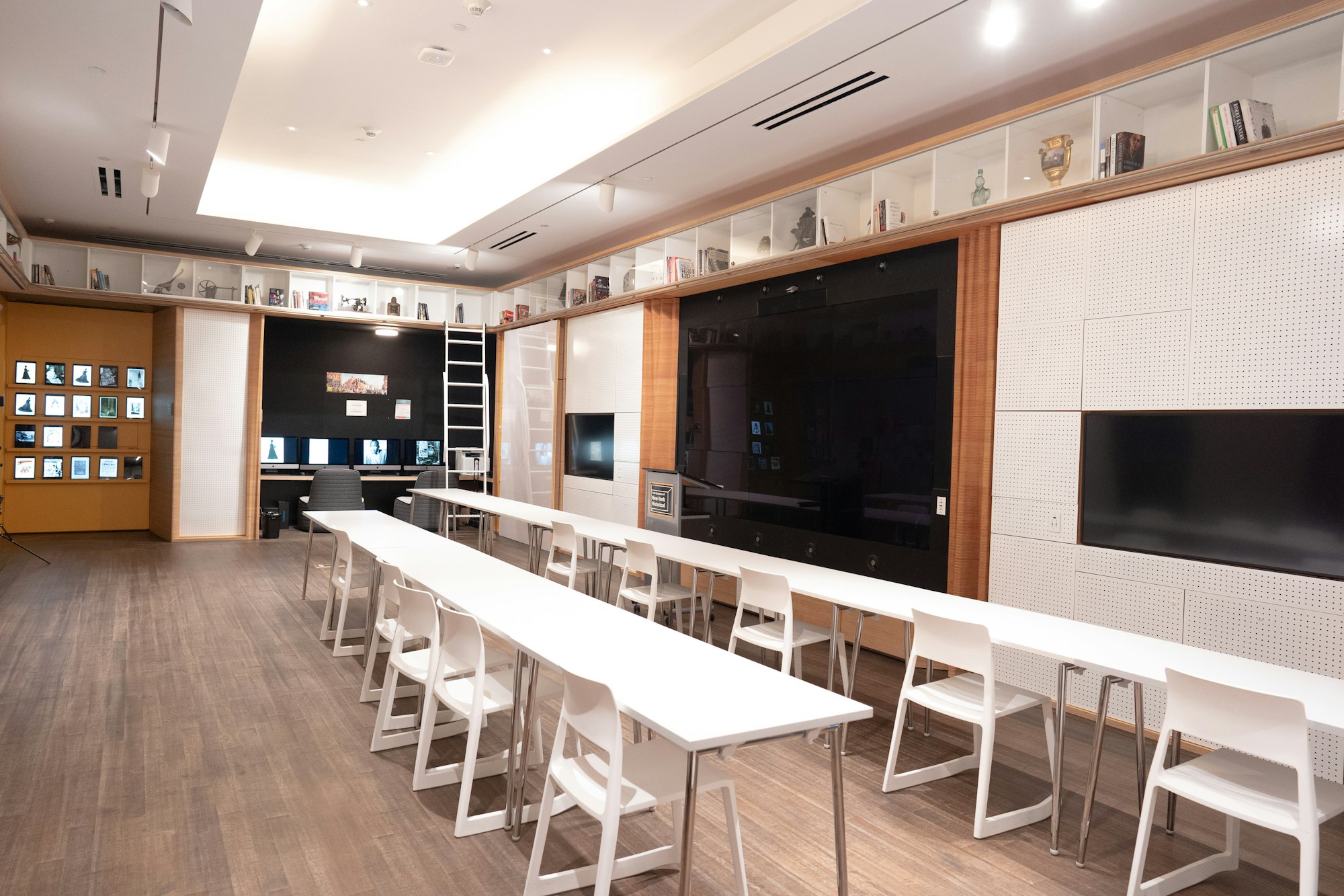 a view of tech commons showing the white tables and the presentation screen