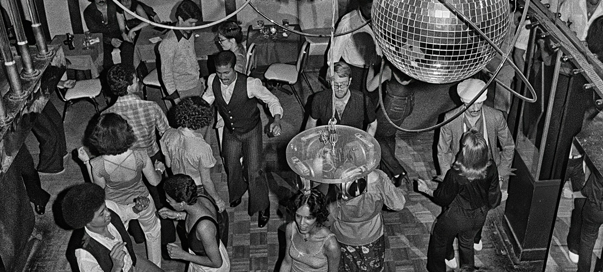 black and white image of a crowded dance floor at a disco in 1979 with multiple couples of various races dancing and several sparkling disco balls hanging from the ceiling
Bill Bernstein, Reflections, 40 East 58th Street, 1979. Photograph (c) Bill Bernstein