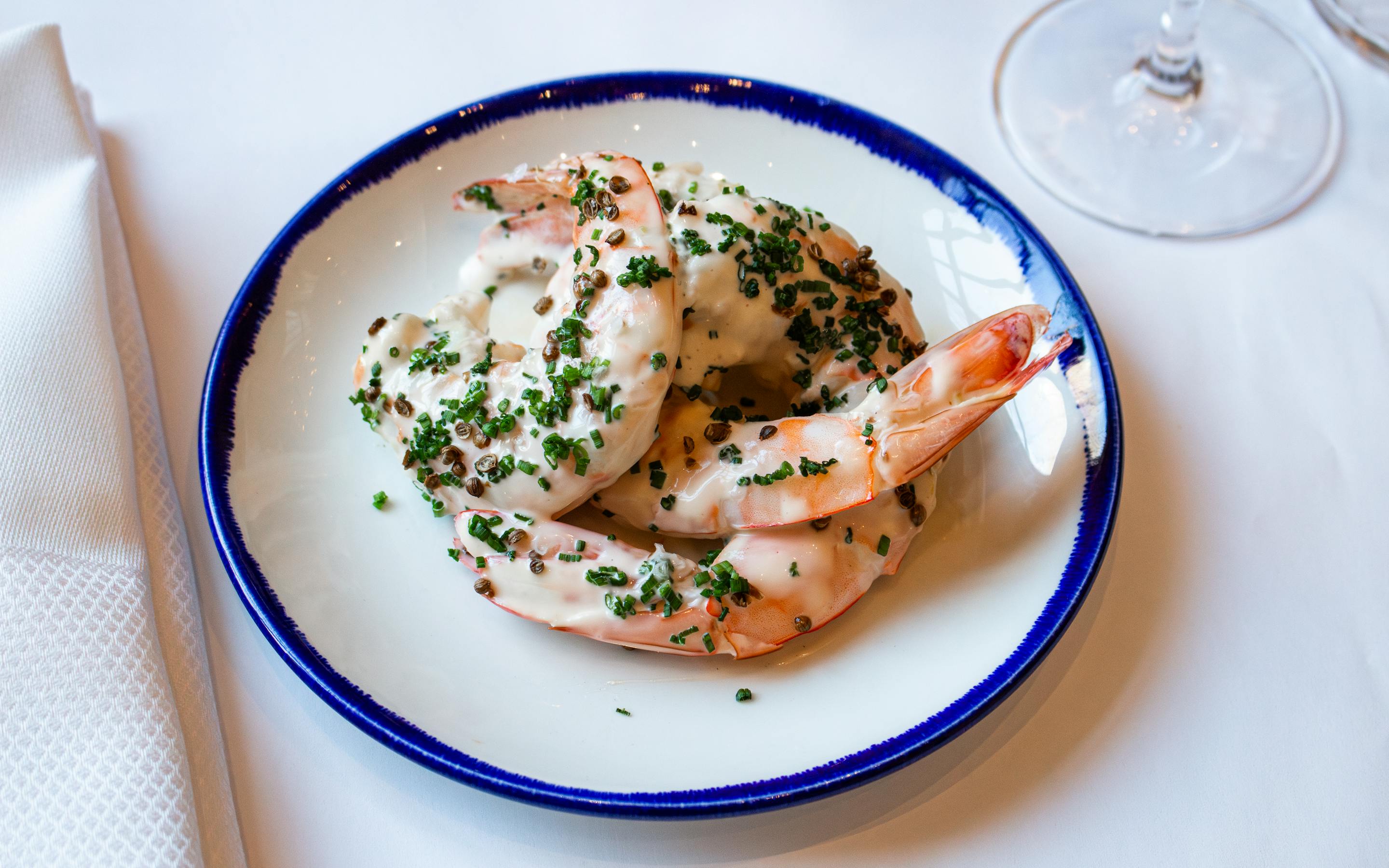 a shrimp dish on a white plate with blue trim