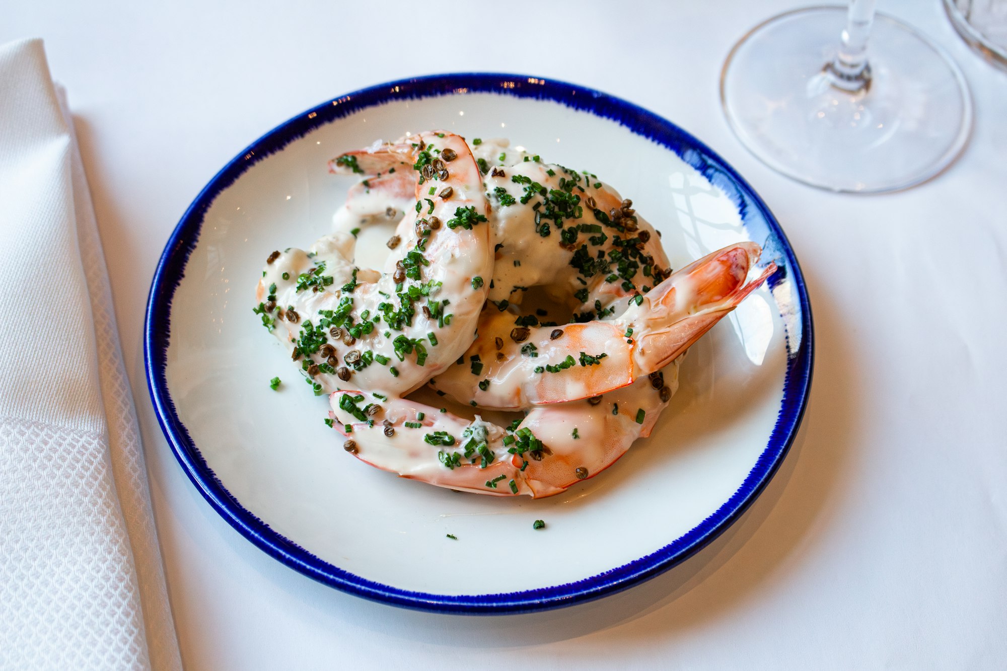 a shrimp dish on a white plate with blue trim