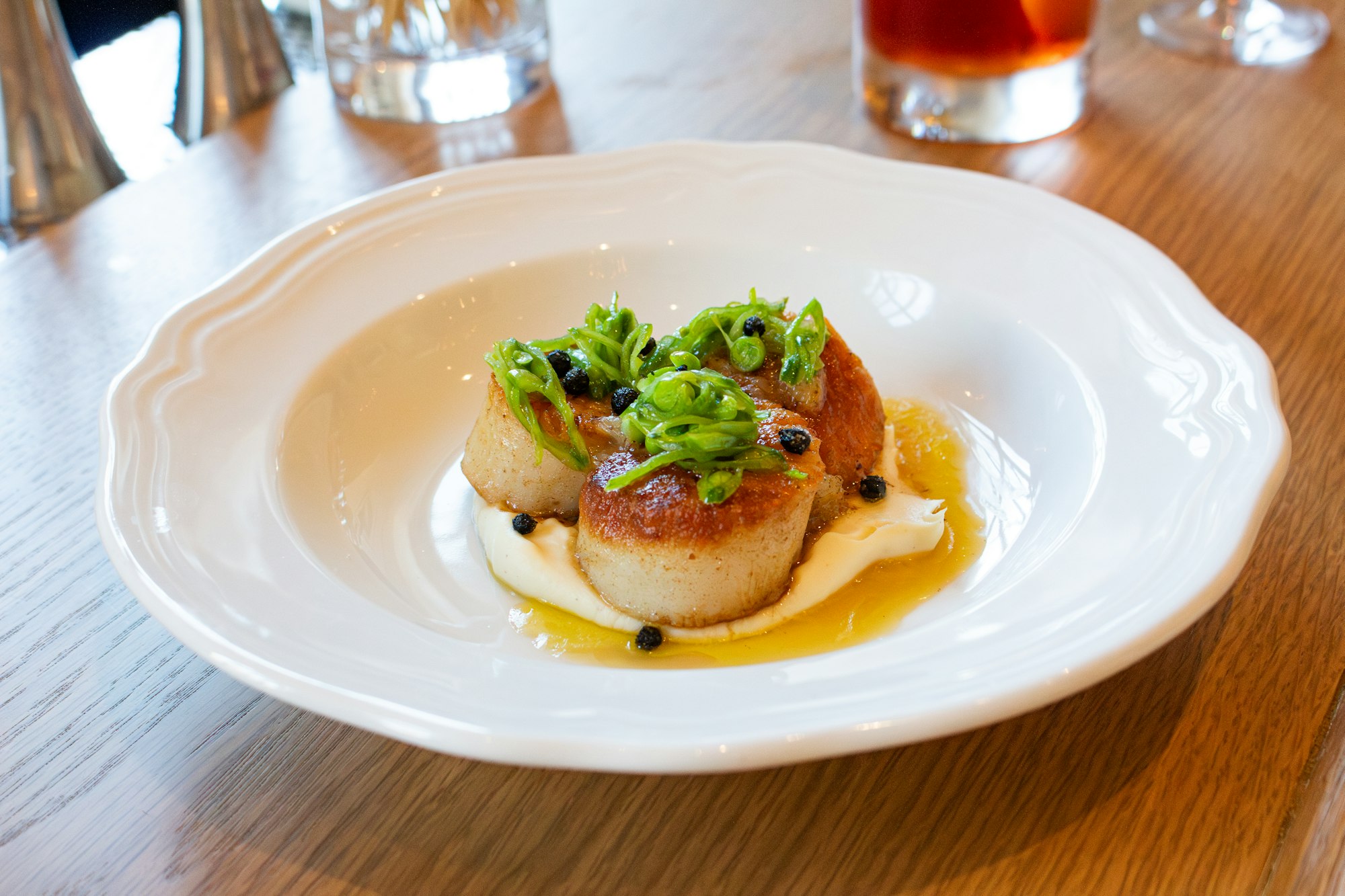 a white plate with seared Diver Scallops in Clara