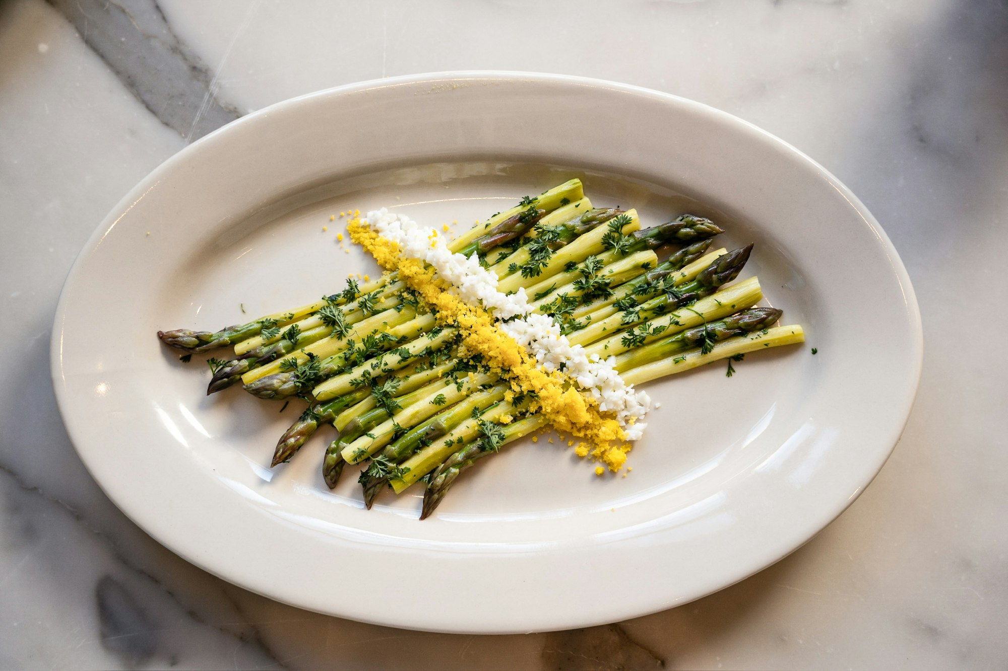 a white plate of asparagus in Clara