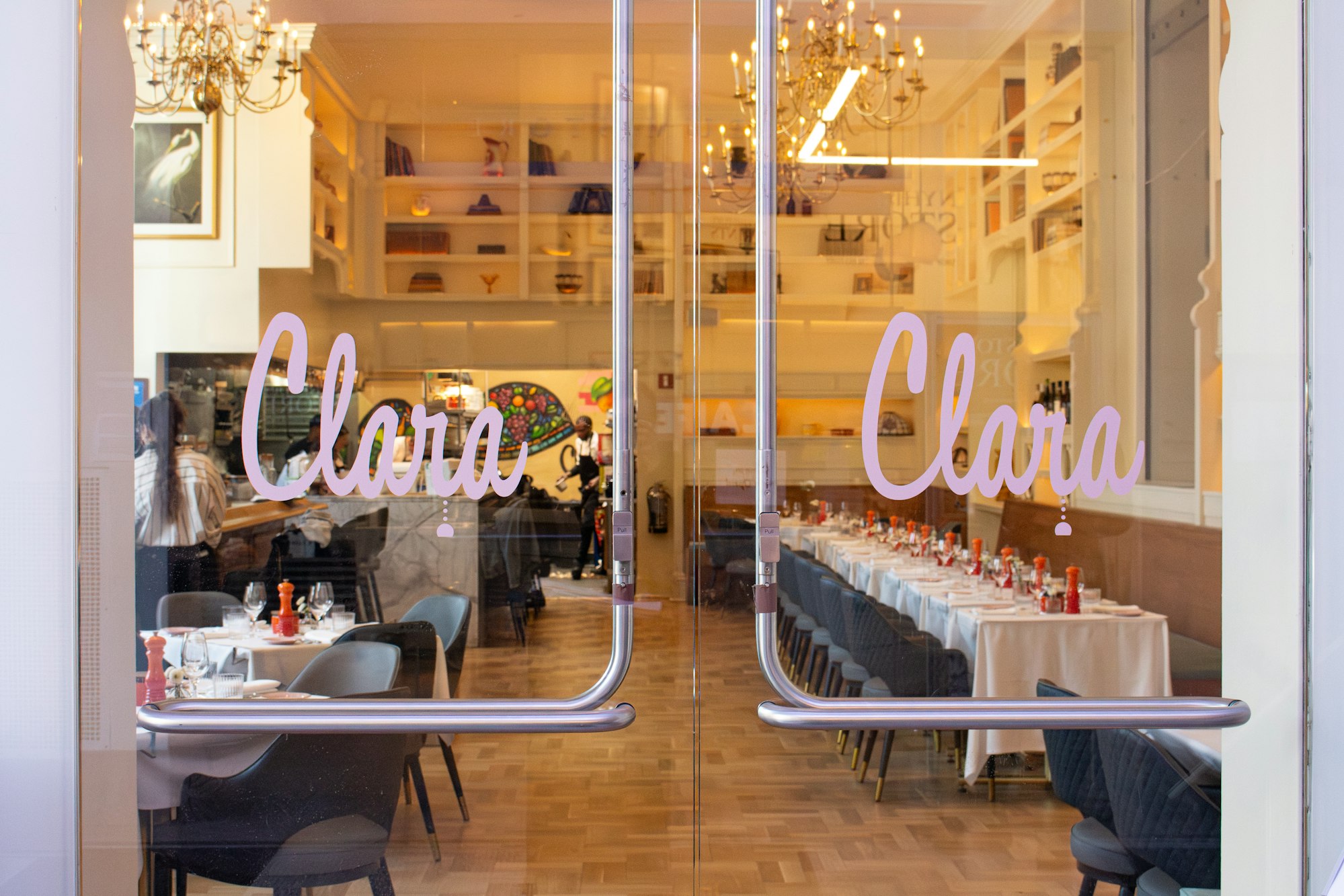 the glass front doors of Clara with the restaurant beyond it.