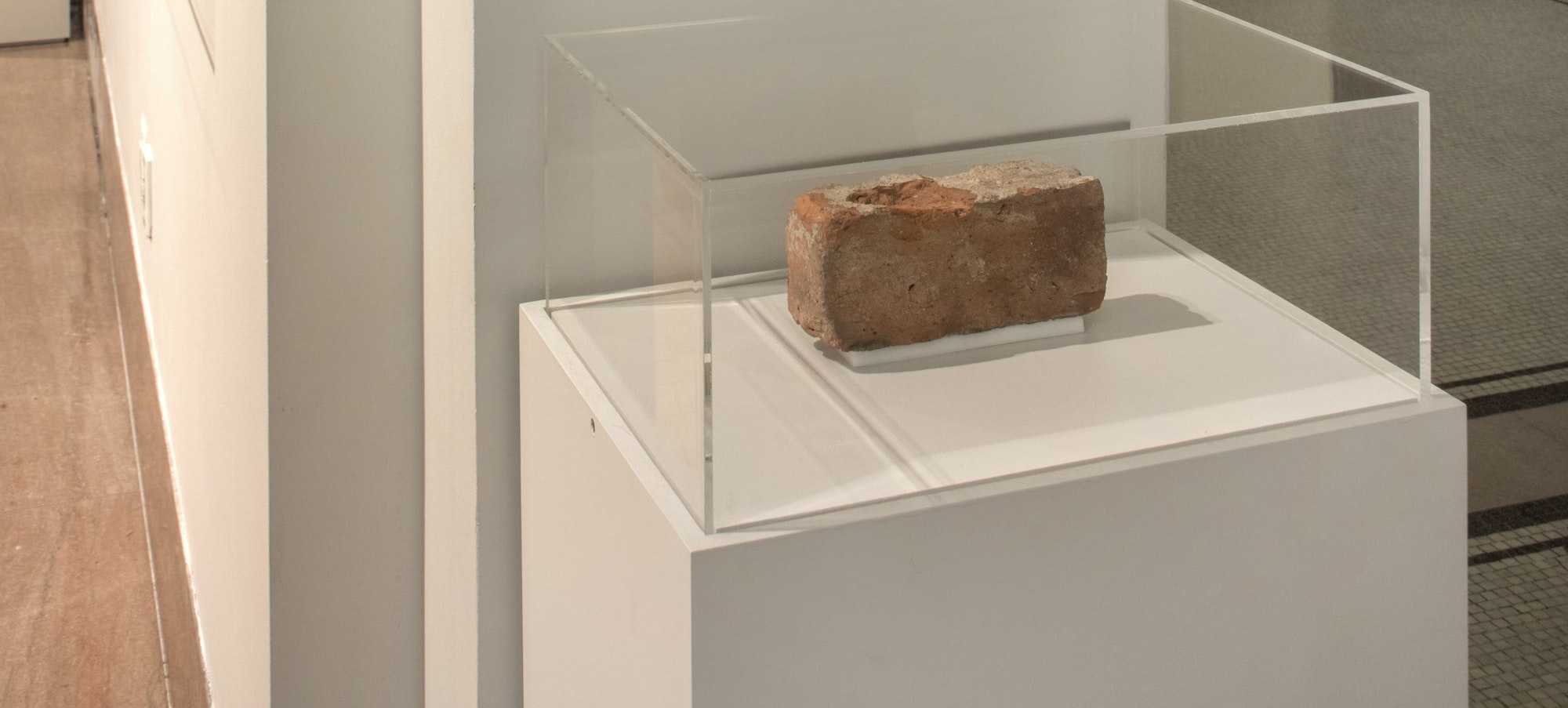 the installation of the Stonewall Brick with a black and white image of the Stonewall bar facade and a brick under a glass case