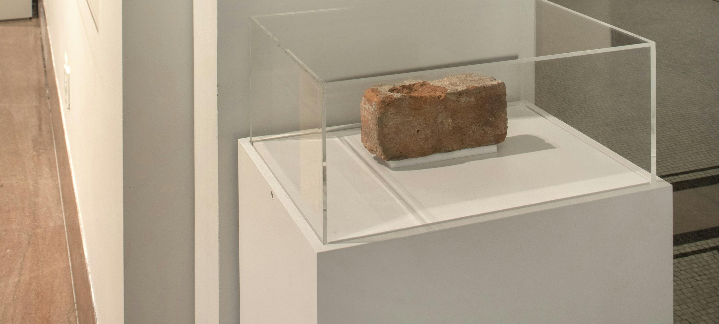 the installation of the Stonewall Brick with a black and white image of the Stonewall bar facade and a brick under a glass case