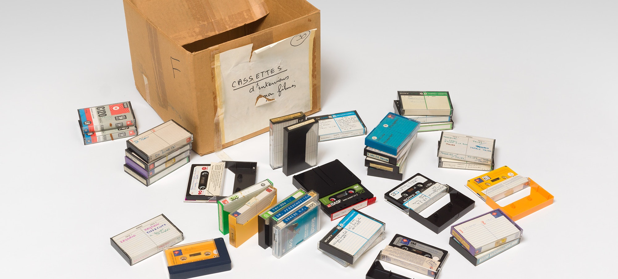 a cardboard box with a number of cassette tapes spilled out in front of it.