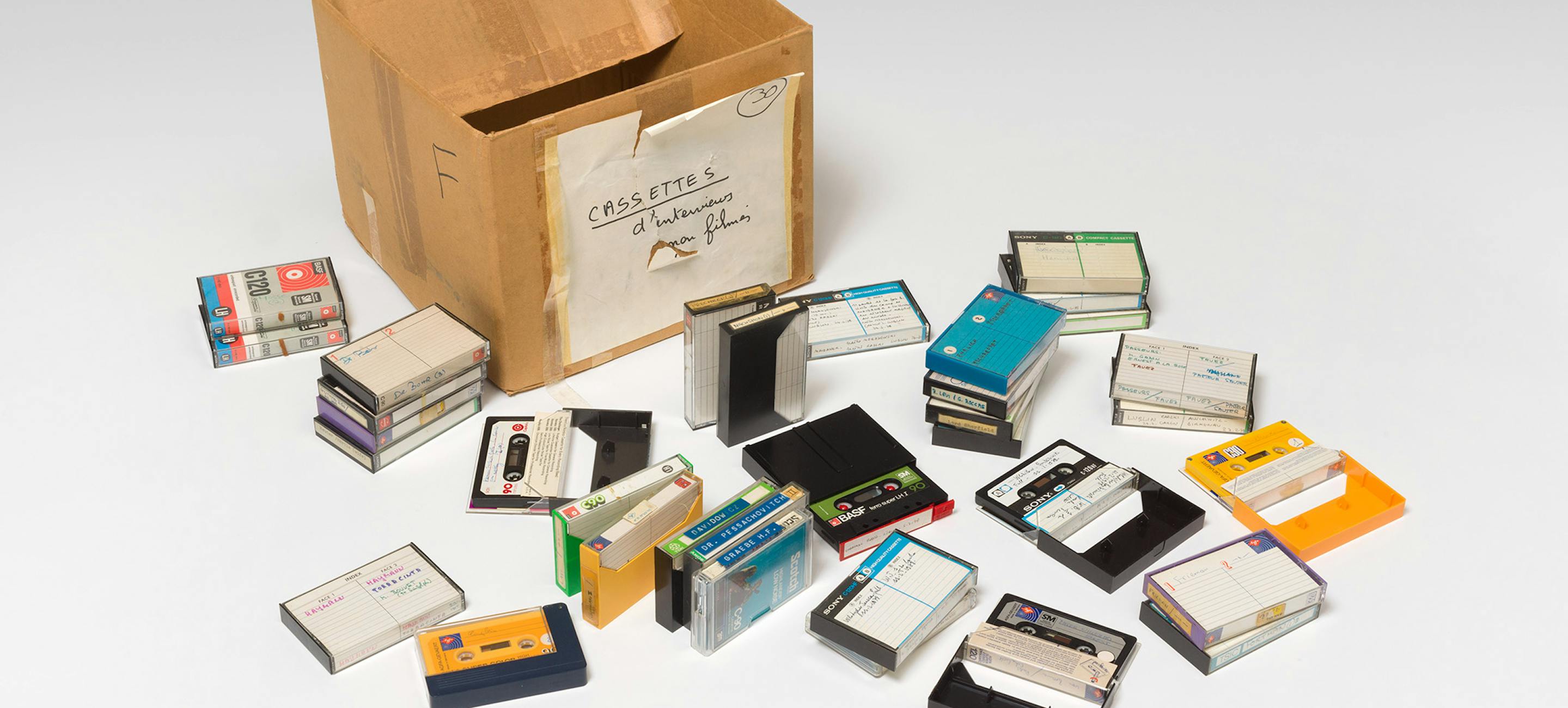 a cardboard box with a number of cassette tapes spilled out in front of it.