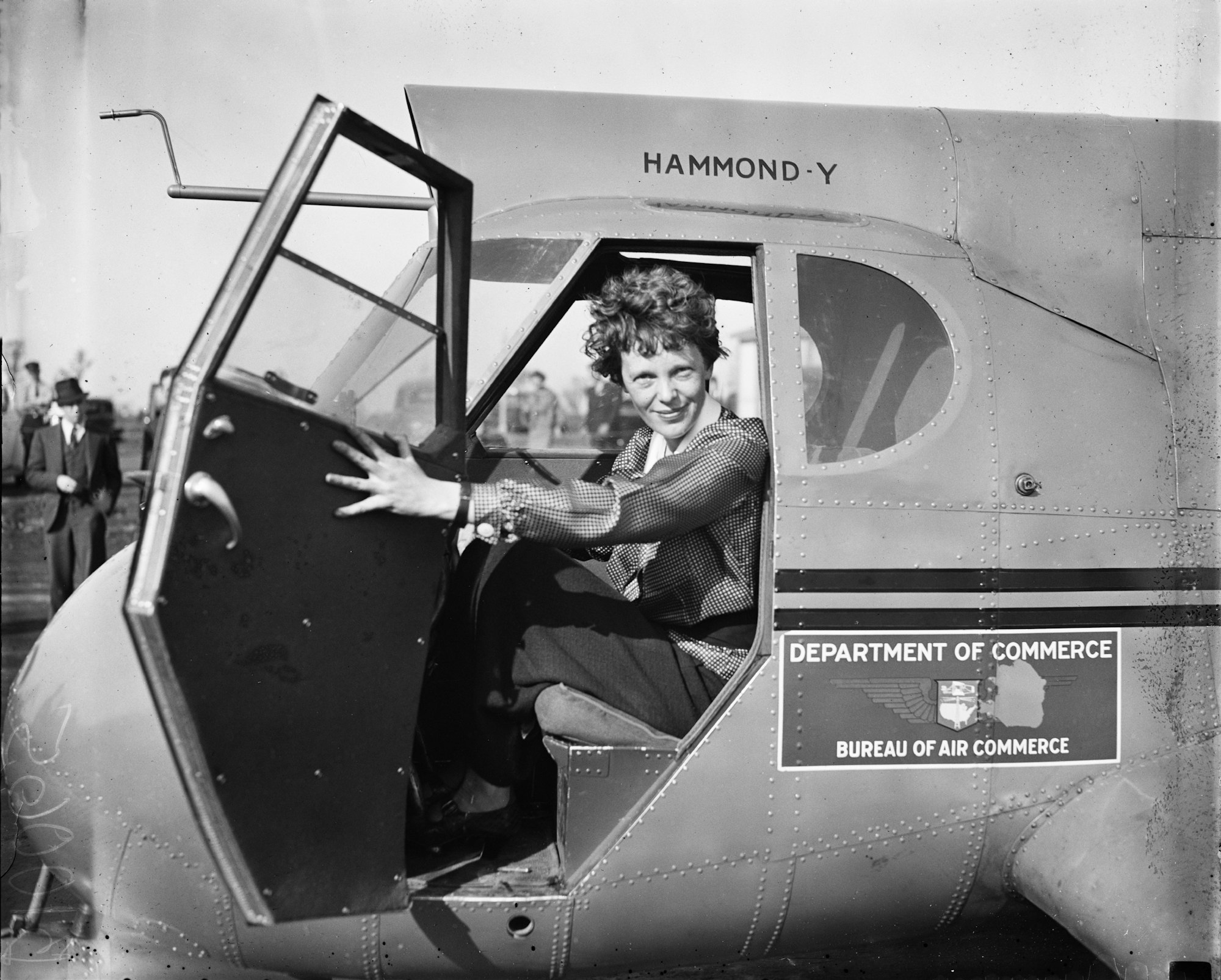 amelia earhart sitting in an airplane cockpit, with the door swung open, 1936, Harris & Ewing - This image is available from the United States Library of Congress's Prints and Photographs division