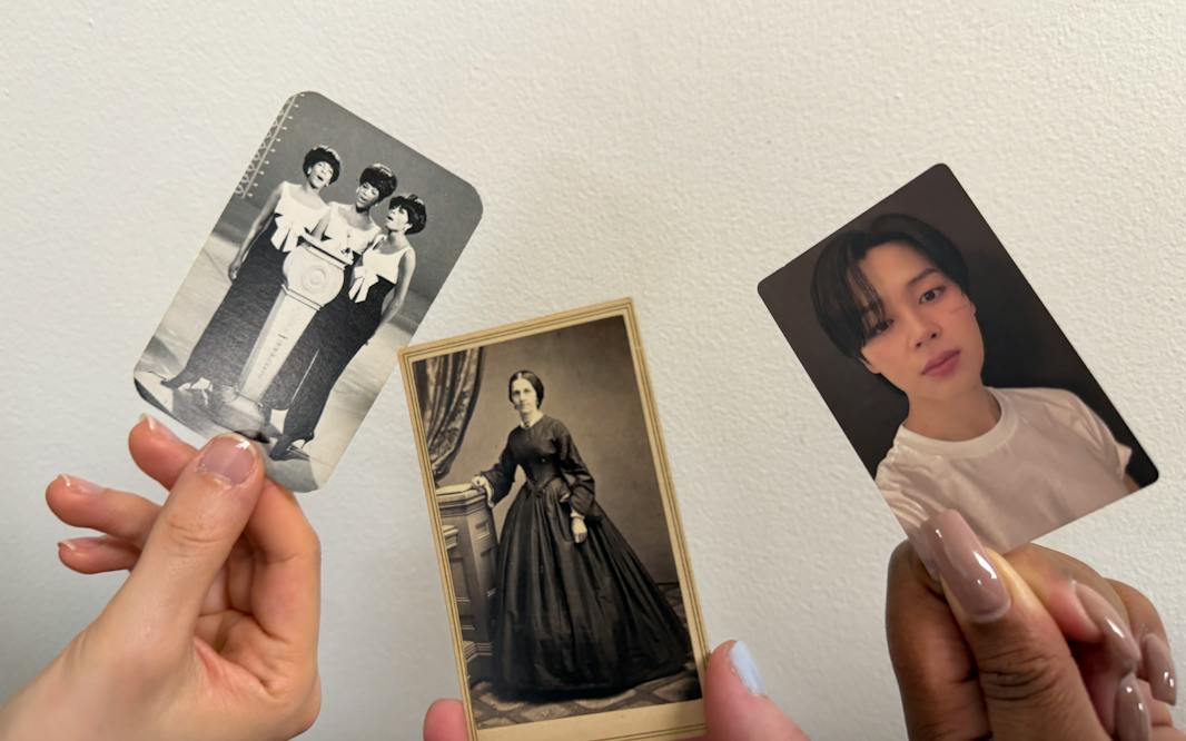 three hands holding up cards with photos of them from different eras.