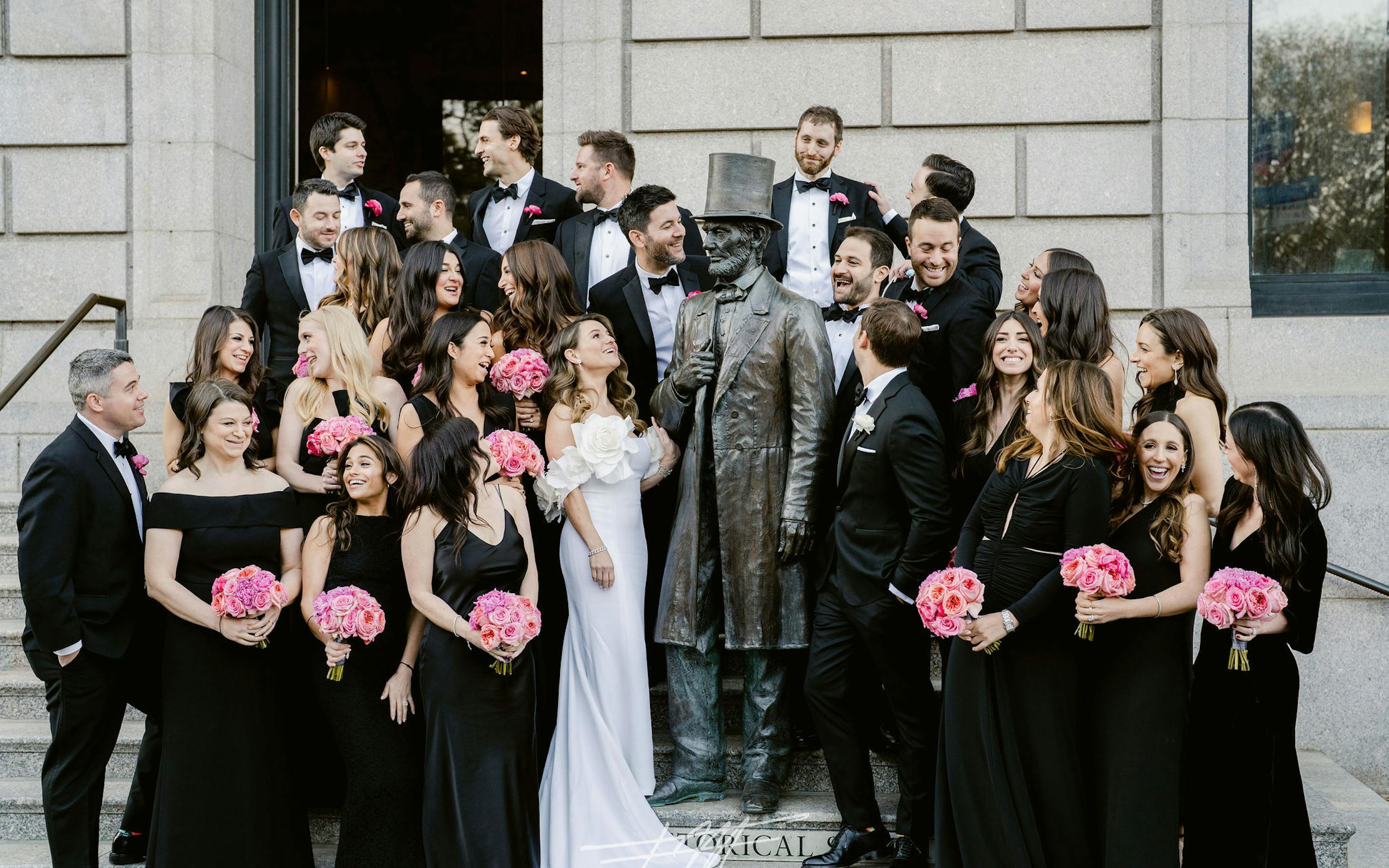 casual, group wedding photo of a wedding party outside on the N-YHS steps around the Lincoln statue