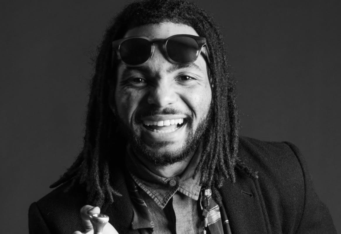 black and white image of Anthony Hervey smiling and holding a trumpet in his hand