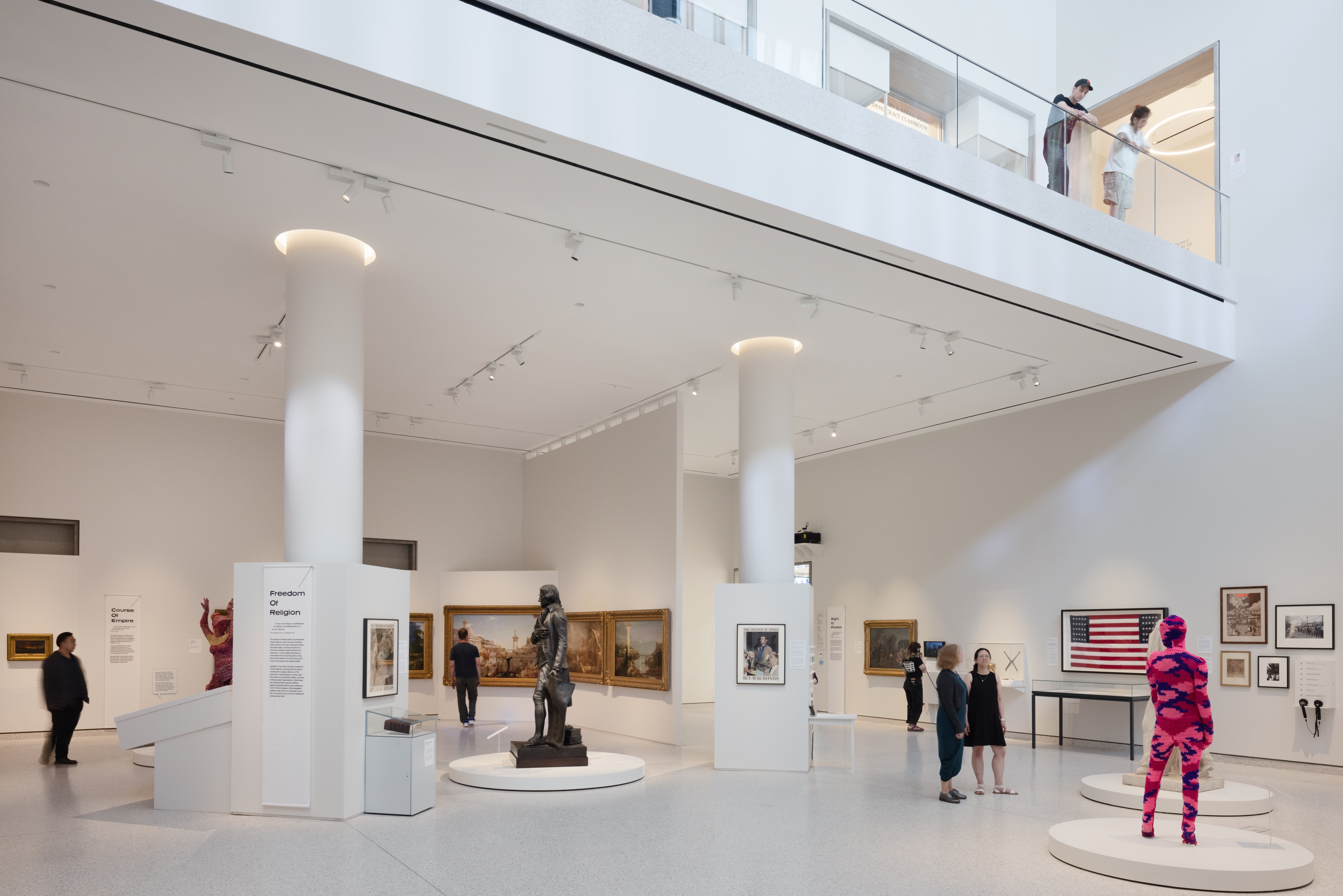 The interior of Klingenstein Family Gallery with art and sculpture for Democracy Matters visible and visitors walking around. Photo by Bridgit Beyer