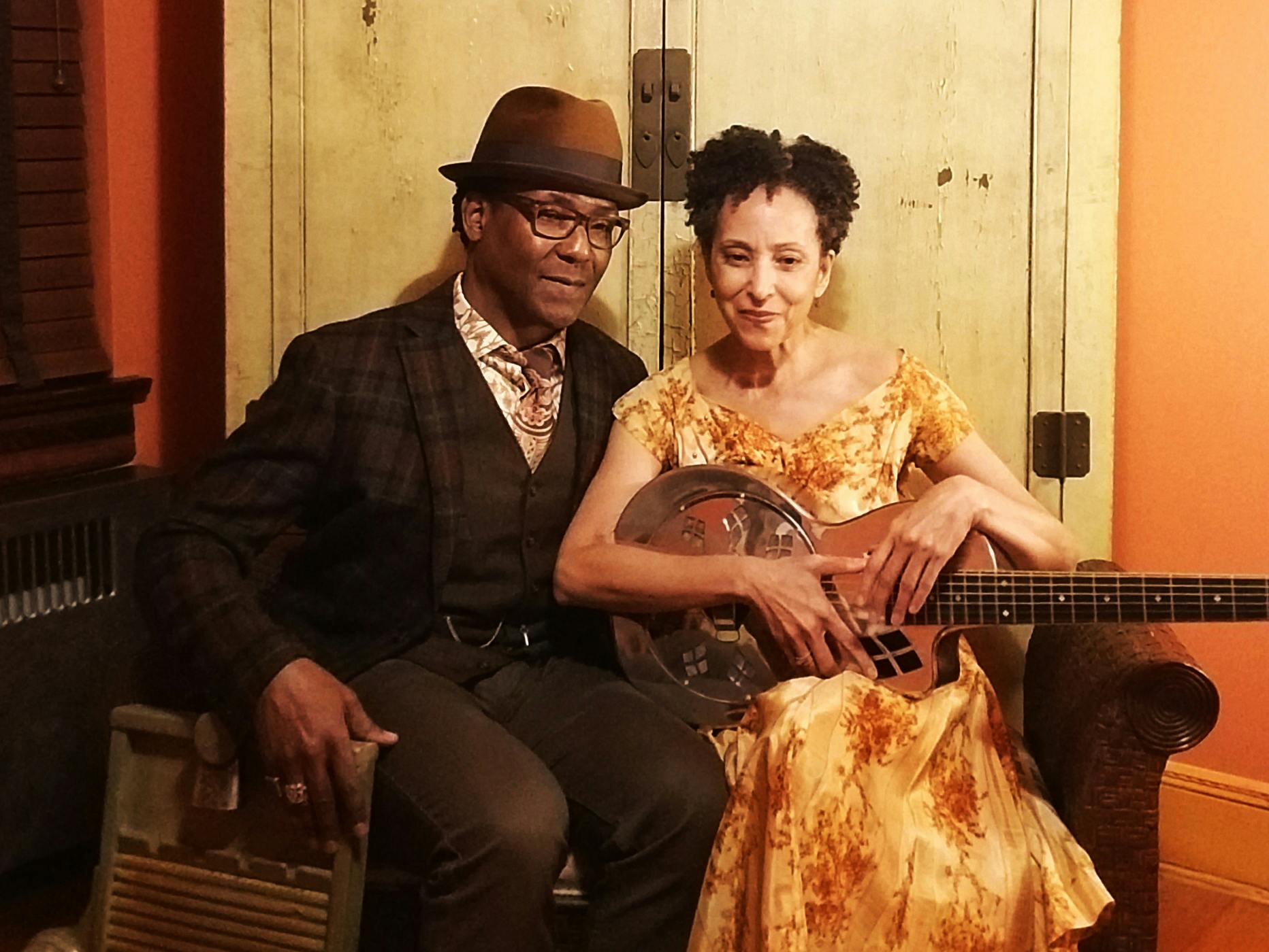 The Piedmont Blūz Acoustic Duo, featuring husband-and-wife Valerie and Benedict Turner, seated, with Valerie holding a guitar