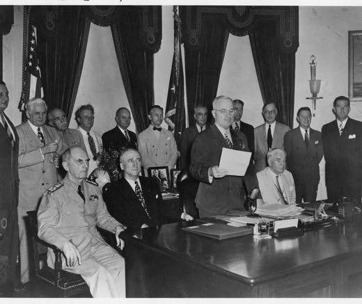 President Harry Truman reads the Japanese surrender message, which effectively ends World War II, surrounded by members of his Cabinet and others, August 14, 1945.