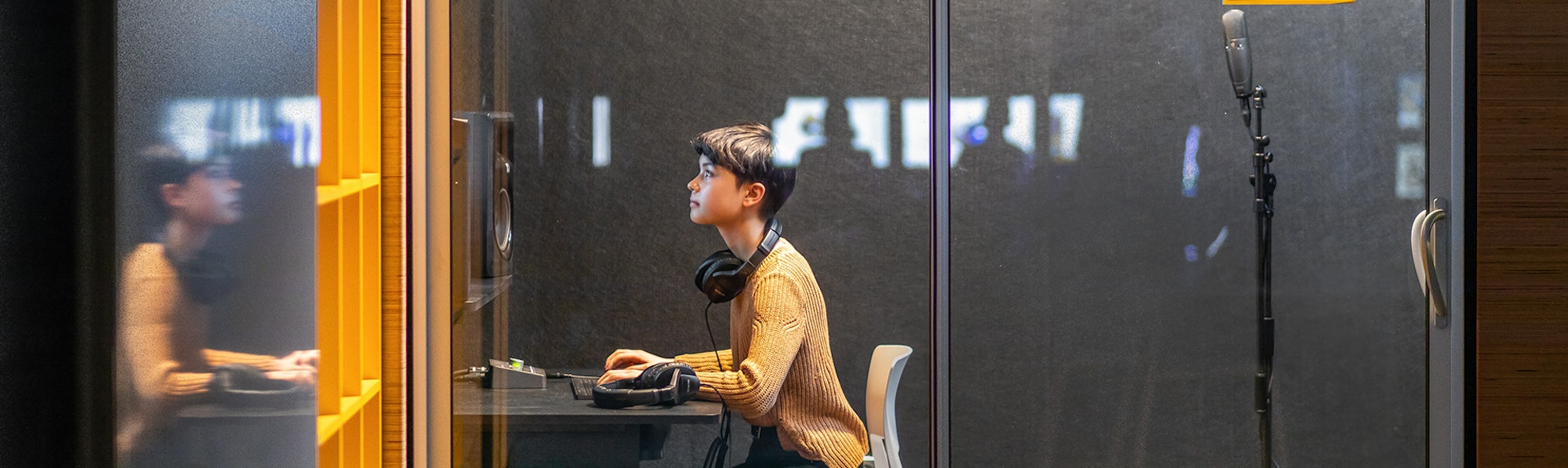 a teen works in the recording booth in the tech commons at New York Historical