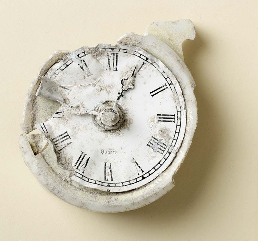 Crushed and broken desk clock, hands stopped at 9:04.