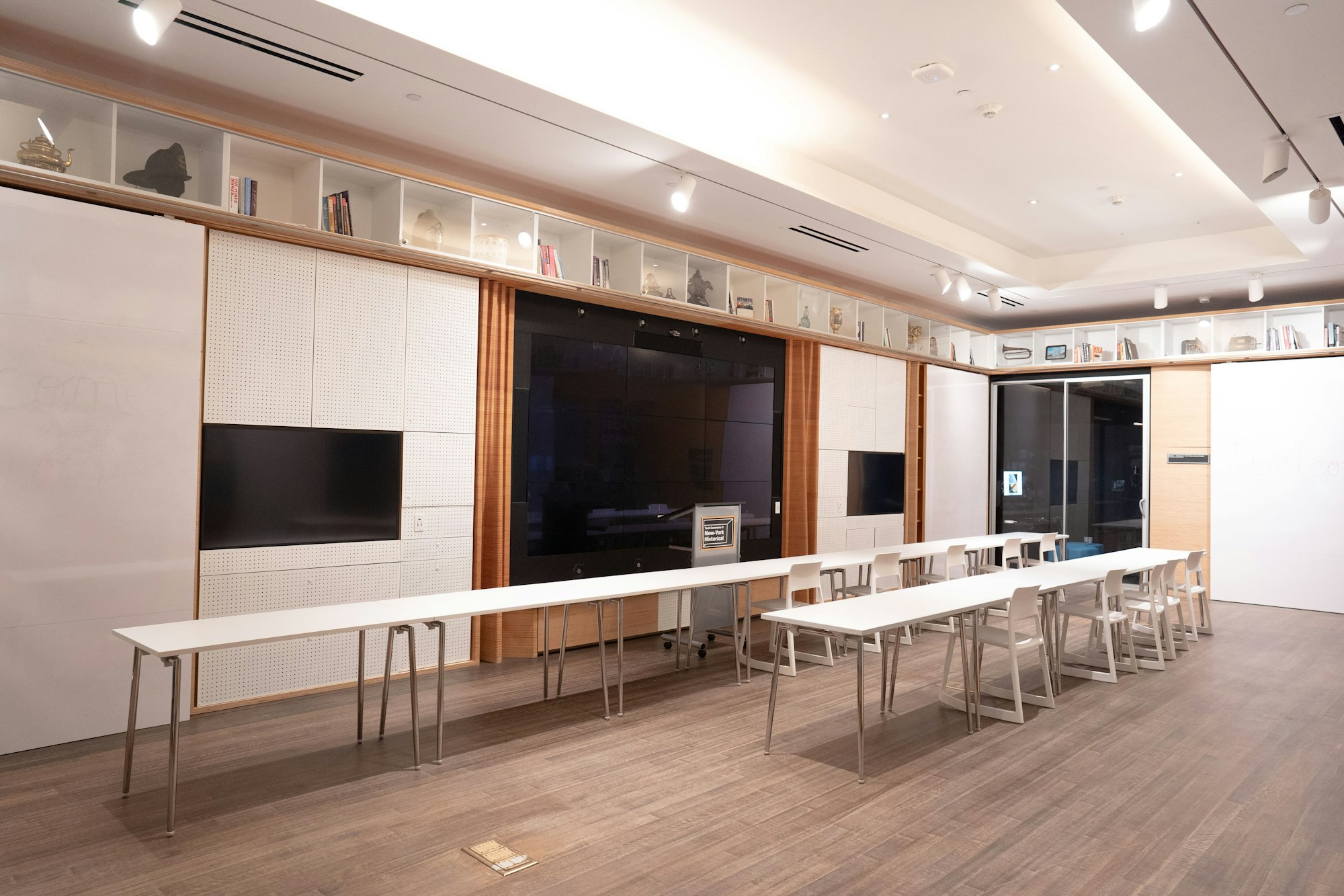 a view of the empty Tech Commons, showing tables and a presentation screen