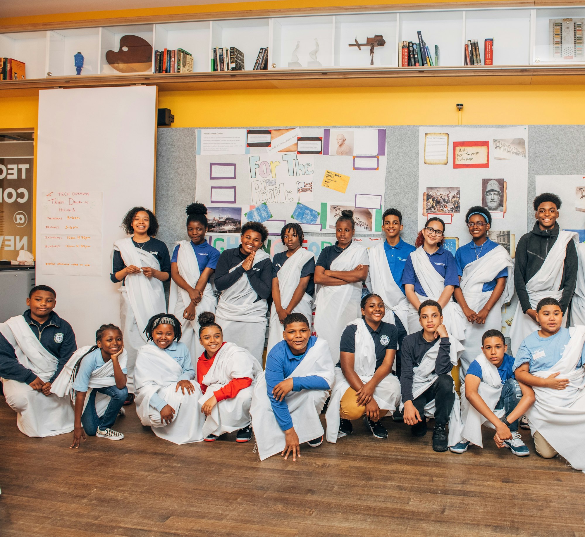 Students in togas standing in front of posters displaying their work.