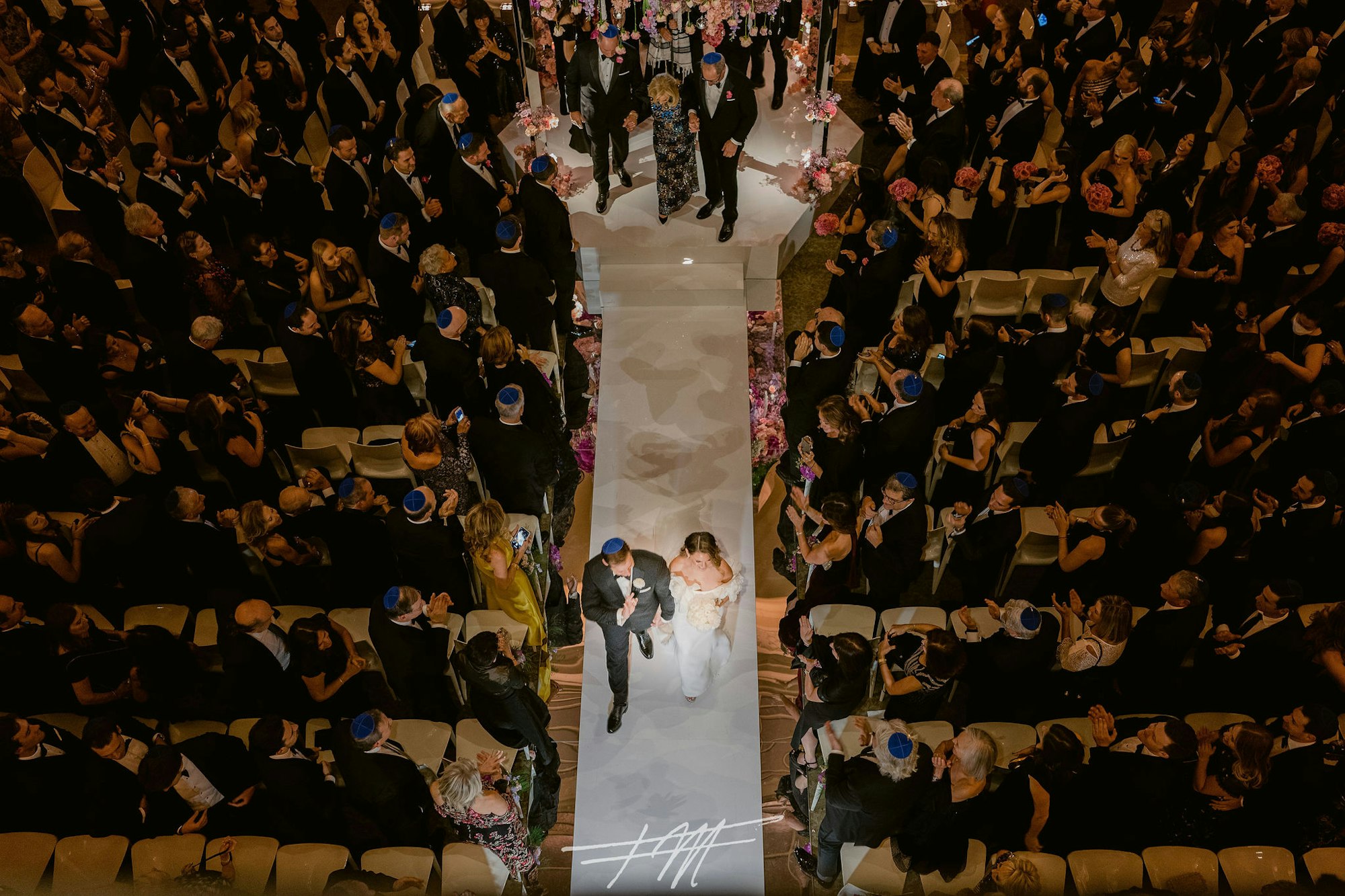 an overhead shot of a couple walking down the aisle surrounded by their guests